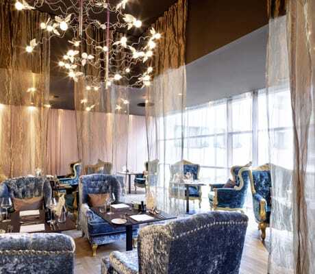 luxuriöse blaue Samtsessel mit goldenen Vorhängen in einem der Restaurantbereiche des GAMS zu zweit