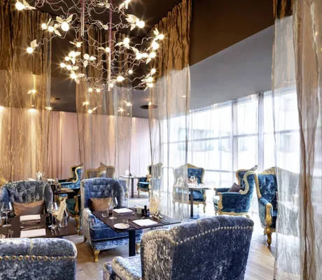 luxuriöse blaue Samtsessel mit goldenen Vorhängen in einem der Restaurantbereiche des GAMS zu zweit