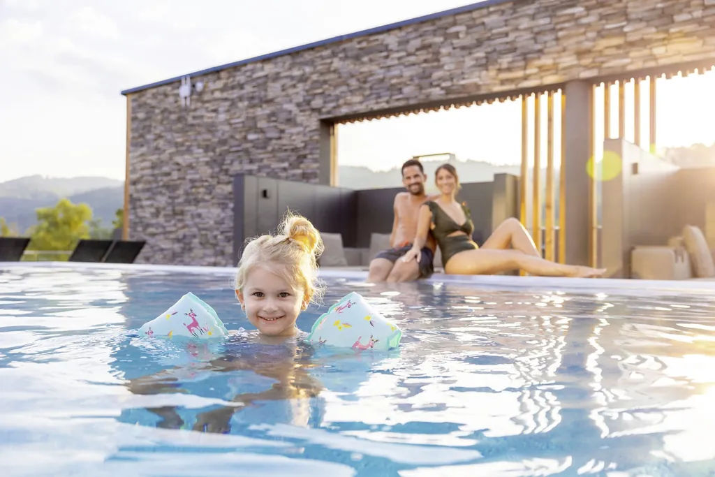 Eltern mit Kleinkind im Au&szlig;enpool des Kinderhotels Schreinerhof