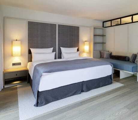 modernes Doppelzimmer im Parkhotel Egerner Höfe mit taubenblauem Bettüberwurf