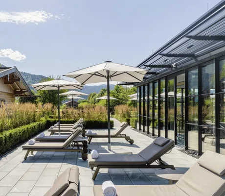 Ruheterrasse im Parkhotel Egerner Höfe mit weißen Sonnenschirmen und Gräsern