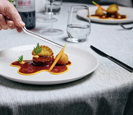 Mit der Pinzette wird eine Karotte auf einem Fleischgericht platziert im Wellnesshotel Jagdhof