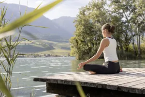 Frau macht Yoga auf der Holzplattform am Kalterer See