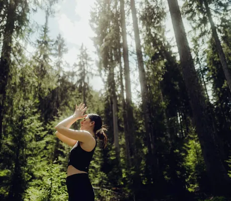 junge Frau macht Yoga im Wald in der Nähe des Holzhotels Forsthofalm