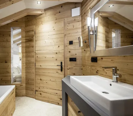 Badezimmer der Liondes Chalets in Holzoptik mit großem Waschbecken und Badewanne