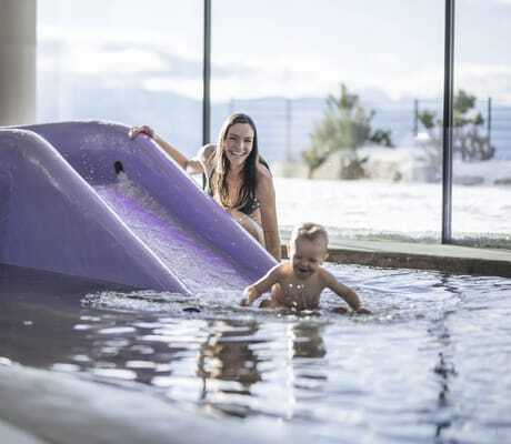 junge Frau mit kleinem Kind in Babypool mit Rutsche des Familienhotels Familiamus
