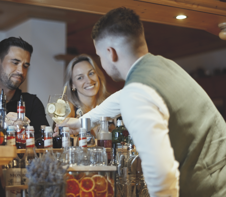 Paar sitzt an der Bar des Bauernhof Hotel Oberschwarzach und erhält vom Barkeeper einen Cocktail