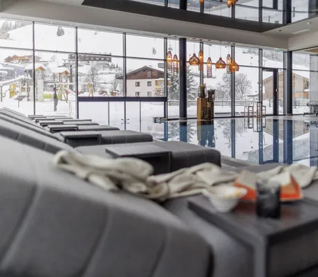 Indoorpool mit Korbhängeleuchten im Bauernhof Hotel Oberschwarzach mit Blick auf die Winterlandschaft