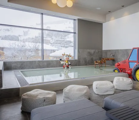 Kinderppol mit rotem Spiel-Traktor und Spiel-Kuh im Bauernhof Hotel Oberschwarzach