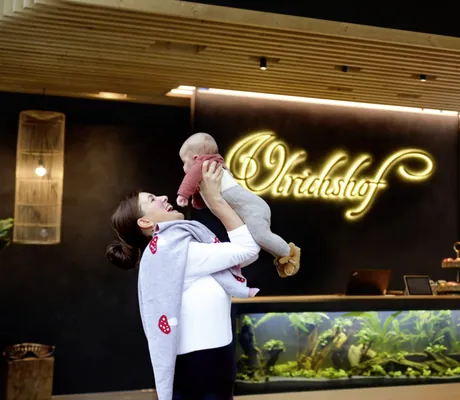 Frau mit Baby in den Armen in der Lobby des Ulrichshof