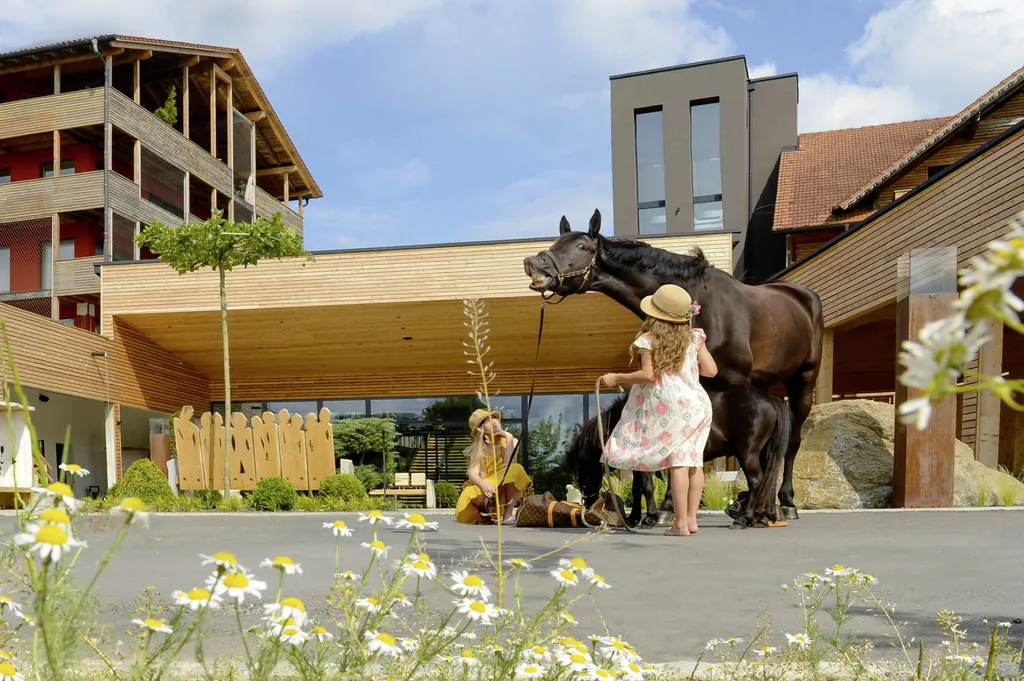 Mädchen mit Hut steht mit Pferd vor dem Eingang des Ulrichshof