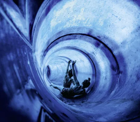 zwei Kinder rutschen im Ulrichshof die blaue Röhrenrutsche hinunter