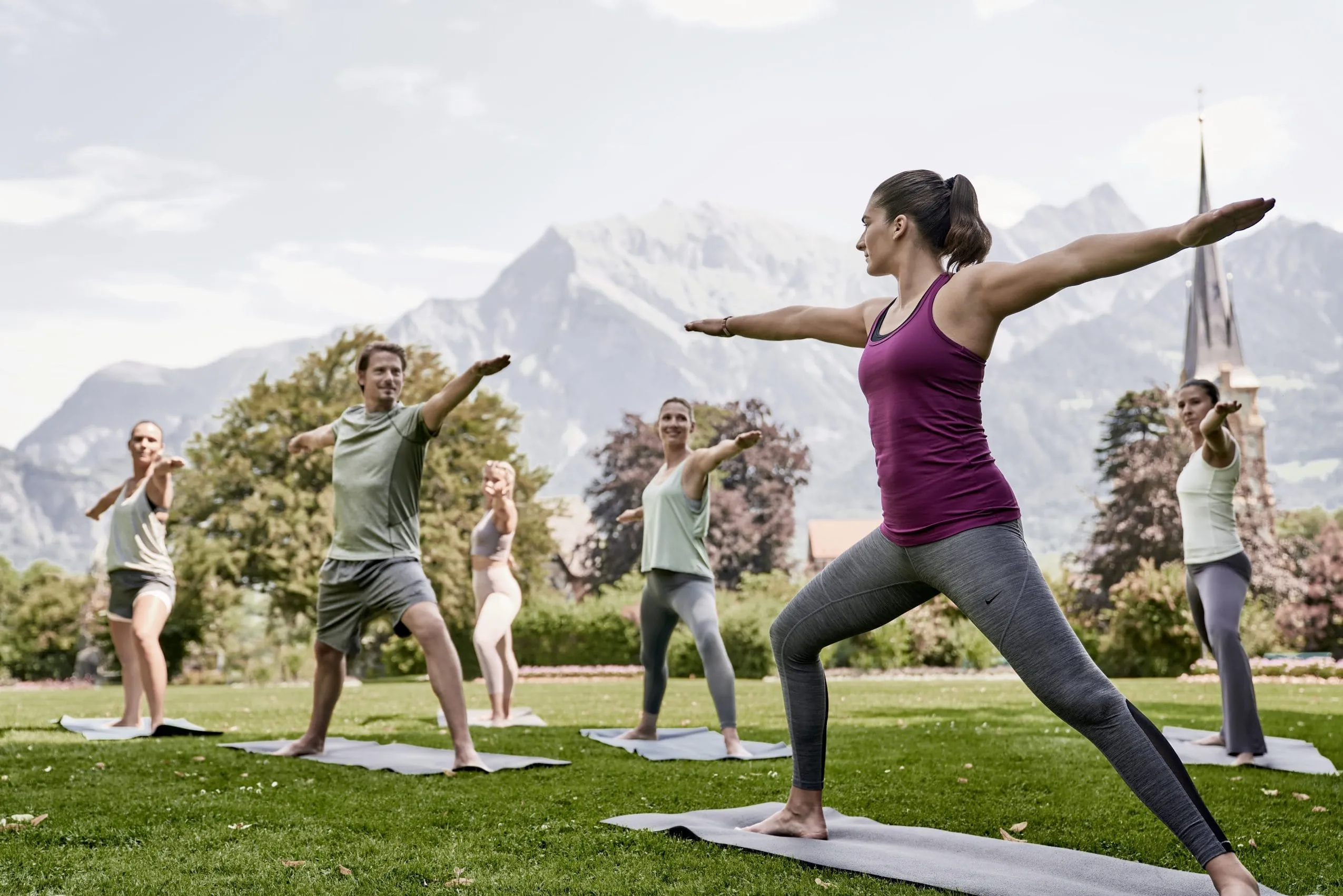 Yogis praktizieren auf Wiese vor Bergpanorama im Grand Resort Bad Ragaz