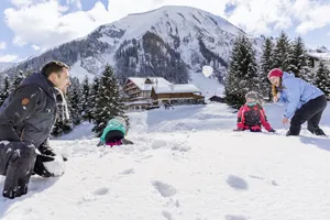 Familie mit zwei Kindern machen eine Schneeballschlacht in der Winterlandschaft des Familotel Kaiserhof
