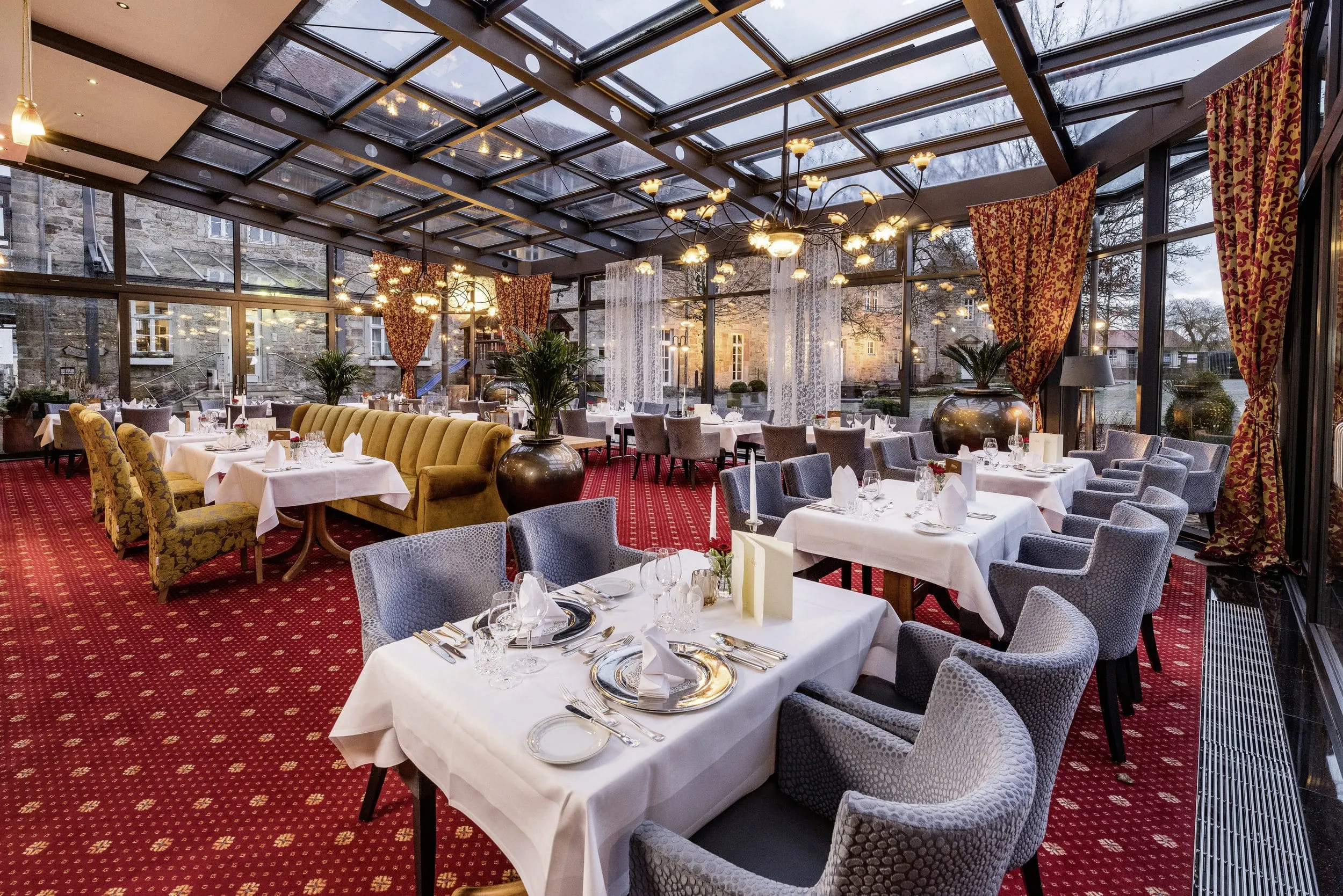 Wintergarten im G&ouml;bel's Schlosshotel Prinz von Hessen mit rot gemustertem Teppich und Glasdach