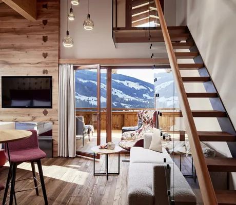 Penthouse Suite mit Holztreppe auf die Galerie und Blick auf den Balkon mit Bergblick im Böglerhof