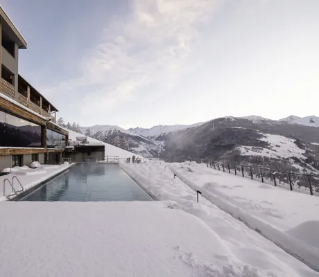 Outdoor-Infinitypool des DAS GERSTL Alpine Retreat im tiefen Schnee mit Blick ins Vinschgau