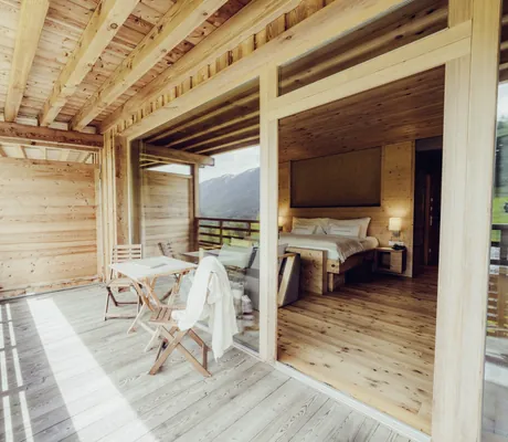 Blick vom Balkon in eines der Zimmer des Holzhotel Forsthofalm mit Doppelbett
