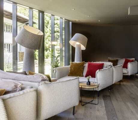 Gemütliche Sofas mit farbigen Kissen und modernen Lampen in der Lobby des Hotel Franks