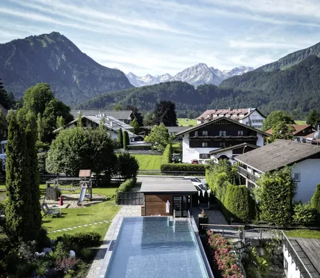 Blick auf den Outdoorpool des Hotel Franks mit Bergpanorama im Hintergrund