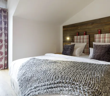 Doppelbett einer Suite im Hotel Franks mit mehreren Kissen und grauer Wolldecke