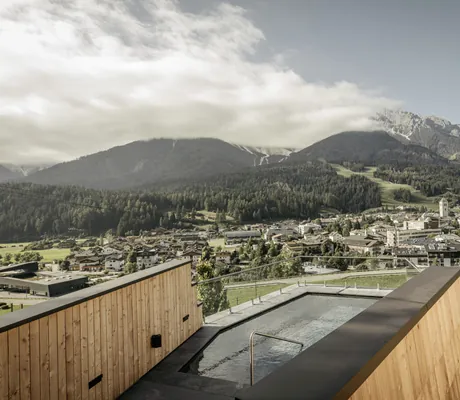 Rooftop-Pool des Naturhotels Leitlhof mit Blick ins Tal und Bergen im Hintergrund