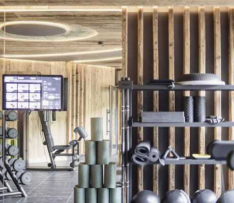 Fitnessraum im Terentnerhof mit Altholzverkleidung und Hantelregal