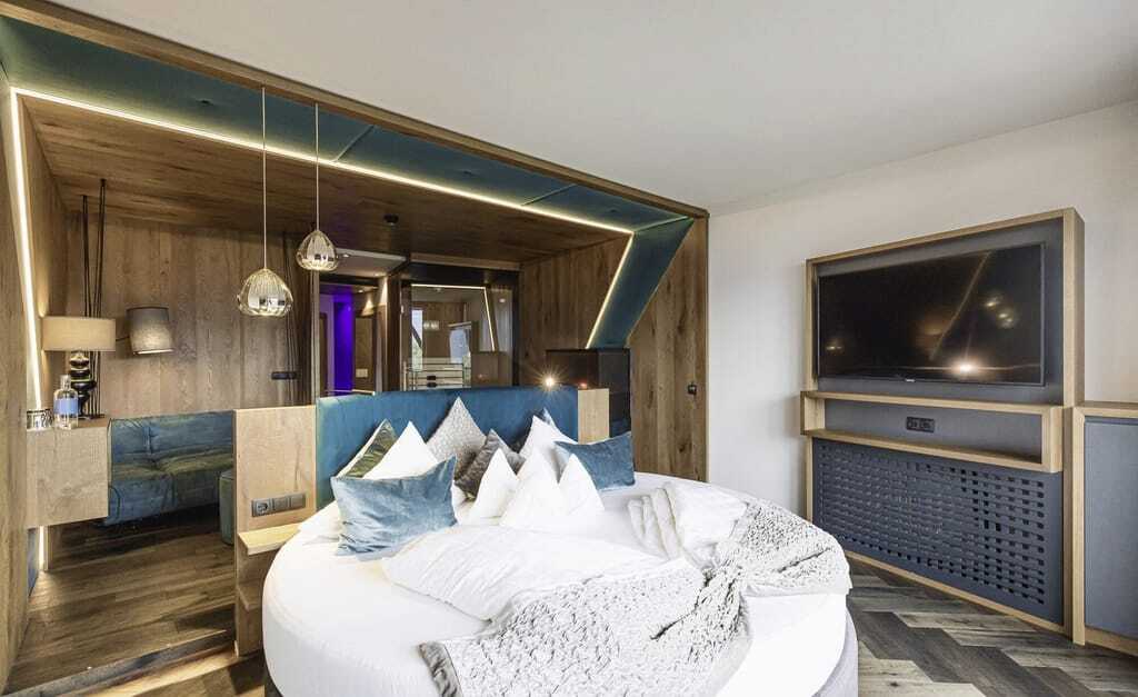rundes Bett mit türkisen Kissen und goldenen Hängeleuchten in der Suite des Terentnerhof