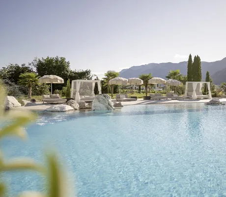 Outdoorpool im Weinegg Wellviva Resort mit weissen Fransen-Sonnenschirmen und weißen Daybeds