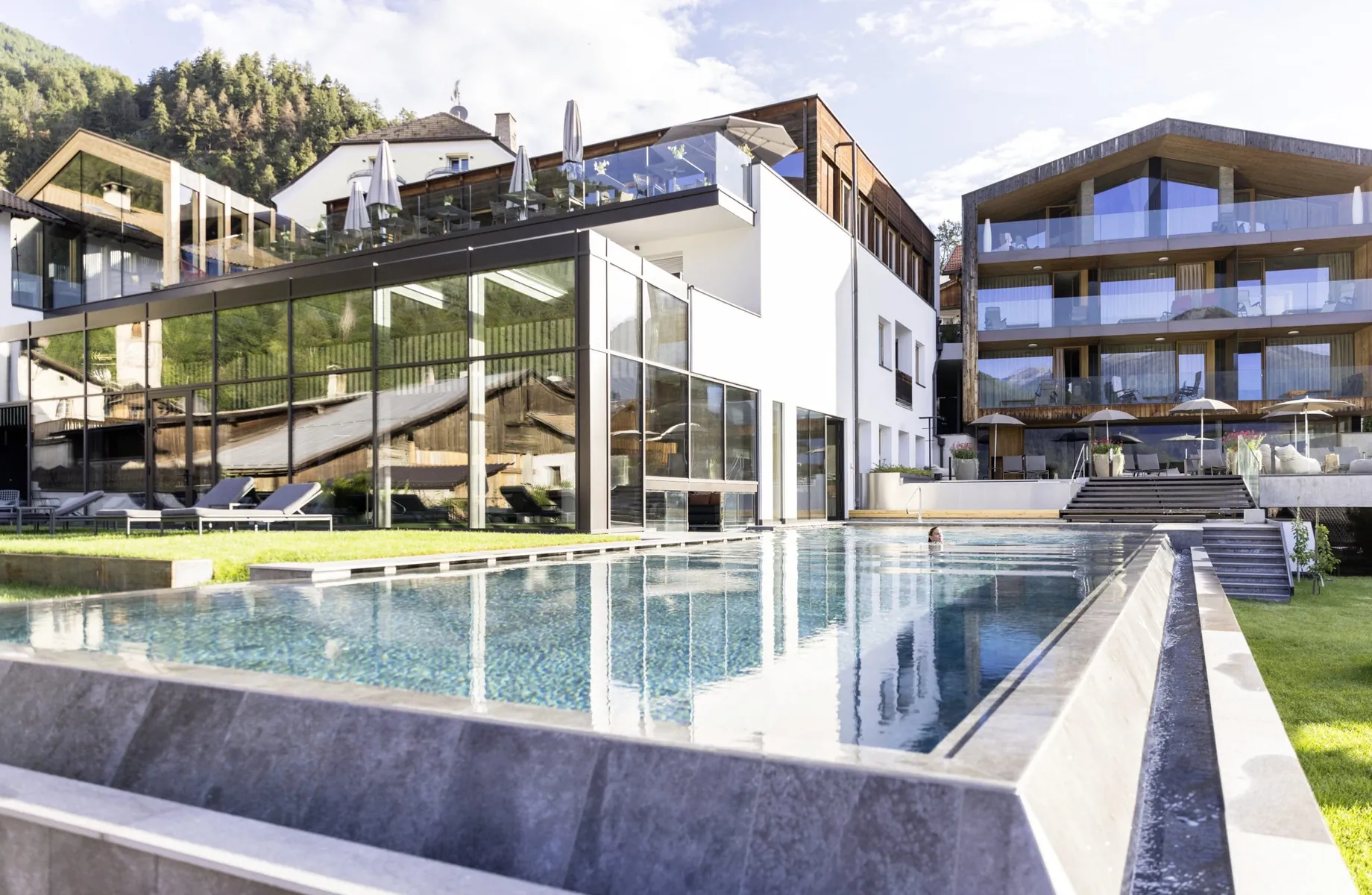 moderne Fassade und Outdoorpool mit schwimmender Frau des Hotel Weisses Kreuz