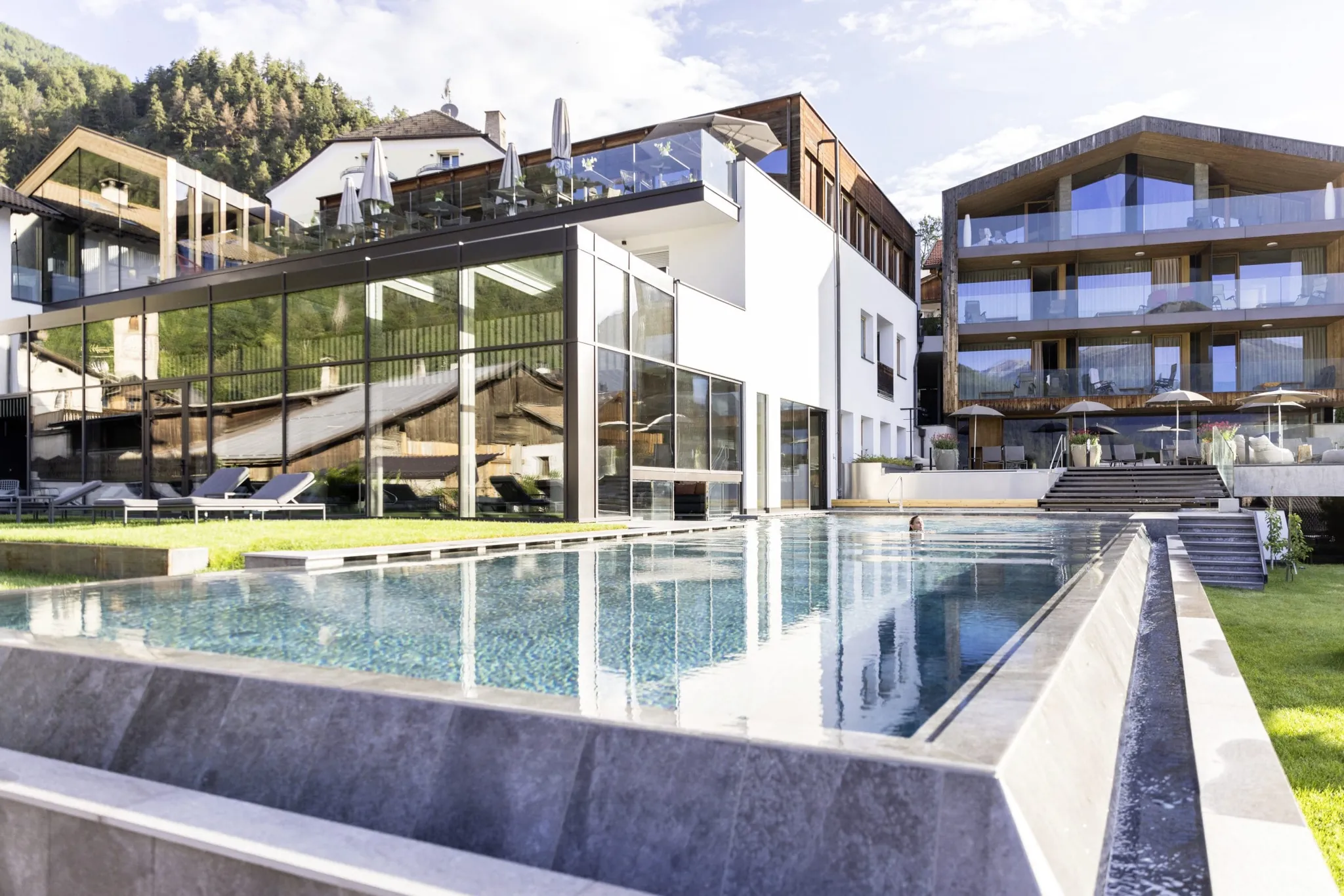 moderne Fassade und Outdoorpool mit schwimmender Frau des Hotel Weisses Kreuz