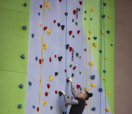 Mann mit Dutt klettert in der Bornmühle an der Kletterwand hoch
