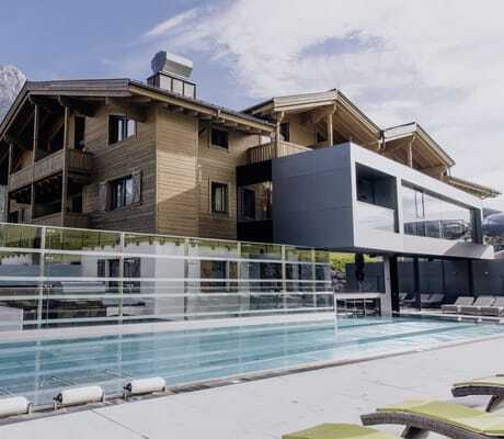 Familien-Außenpool mit Blick auf die Fassade der Riederalm im Sommer