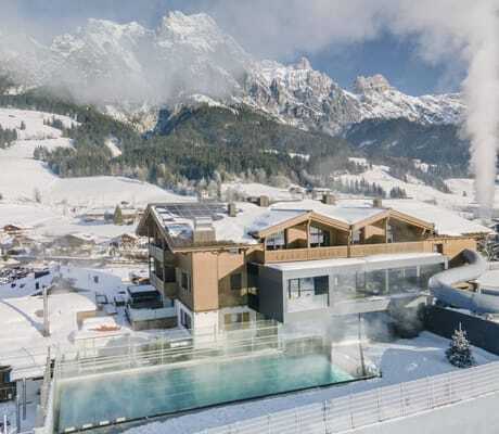 Familien-Außenpool mit Blick auf die Fassade der Riederalm im Winter von oben