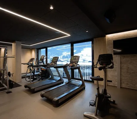 Laufbänder im Fitnessraum der Riederalm mit Blick auf verschneite Landschaft