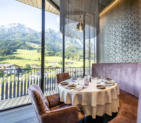 Restaurantnische mit braunen Ledermöbeln und Hängeleuchte mit Perlen in der Riederalm