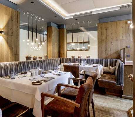 Restaurant mit gedeckten Tischen und gestreiften Sitzpolstern in der Riederalm