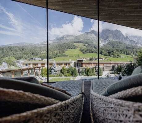 Korbsessel vor dem großen Panoramafenster mit Blick auf die Berge vor der Riederalm