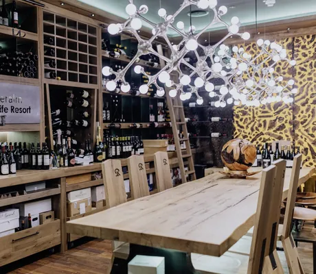 Weinkeller mit großer Designerleuchte über dem Holztisch über der Riederalm