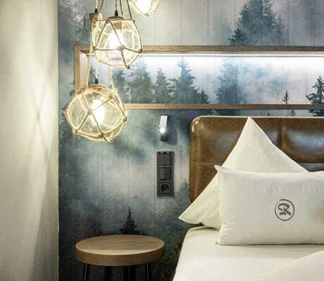 Bett-Detail mit Baumtapete und runden Glaskugeln in der Riederalm