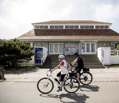 Zwei Radfahrer vor einem historischen Gebäude mit der Aufschrift Kunsthalle Kühlungsborn in der Nähe der Villa Astoria