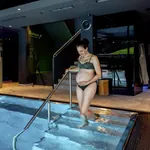 schwangere Frau im Bikini geht die Treppe des Thermalpools im Good Life Resort Riederalm hinunter