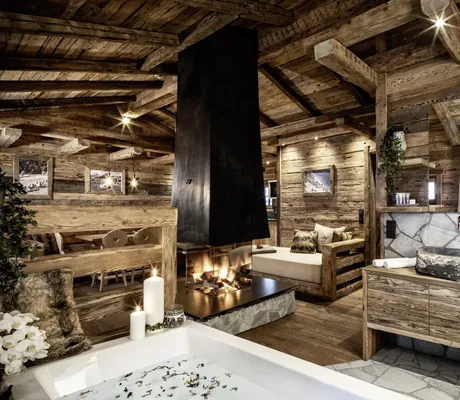 Blick in das urige Bergchalet des Bergdorf Prechtlgut mit Badewanne, zwei Naturstein-Waschbecken, verglastem Kamin und Sitzmöglichkeiten