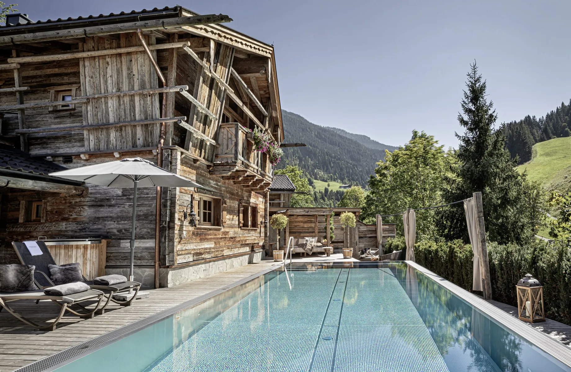 Blick auf den privaten Außenpool und die Pool Luxury Lodge des Bergdorfs Prechtlgut mit Sonnenliegen und Sonnenschirm