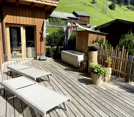 Blick auf die Terrasse eines Chalets des Farm Resorts Geislerhof mit zwei Sonnenliegen