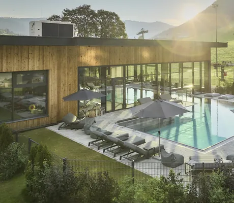 Außenpool im Bauernhof Hotel Oberschwarzach mit grauen Liegen am Rand