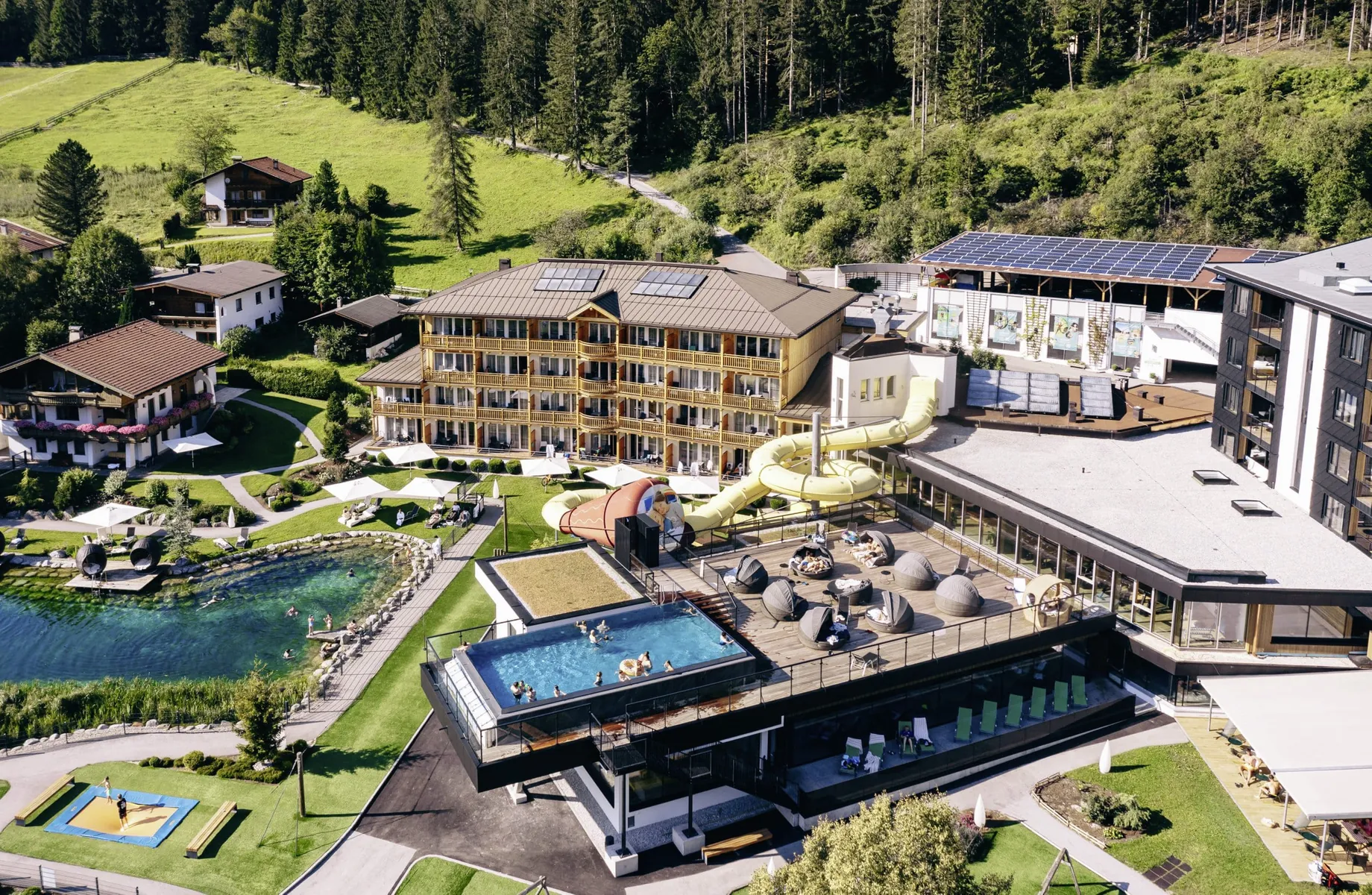 Blick auf die gesamte Hotelanlage des Familienresort Buchau mit Infinitypool, Reifenrutsche, Relaxkojen, Trampolin und Naturbadeteich
