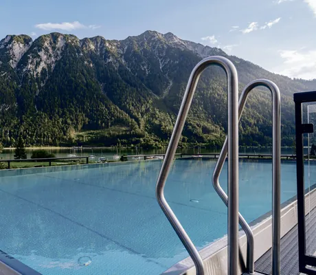 Blick vom Outdoor-Infinitypool auf dem Sonnendeck des Familienresort Buchau auf umliegende Berge und Achensee