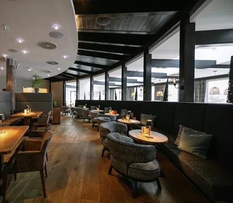 Schickes Restaurant mit grauen Sitzgarnituren und kleinen Stehlampen auf den Tischen des Familienresorts Buchau