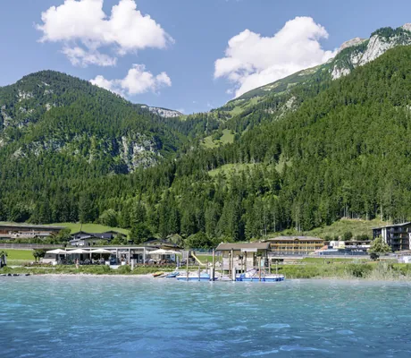 Blick auf die Hotelanlage des Familienresort Buchau mit Achensee im Vordergrund und Bergen im Hintergrund